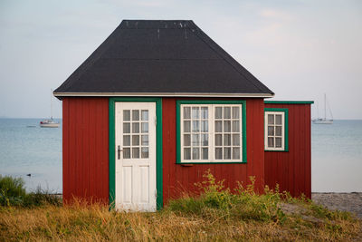 Built structure on beach by house against sky