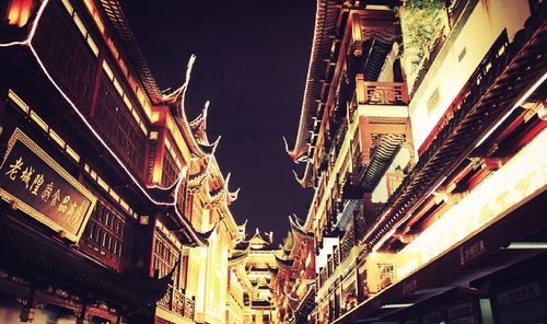 Low angle view of illuminated buildings against sky at night