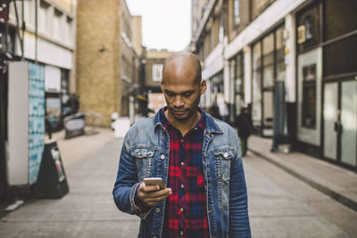 Young man using smart phone standing in city