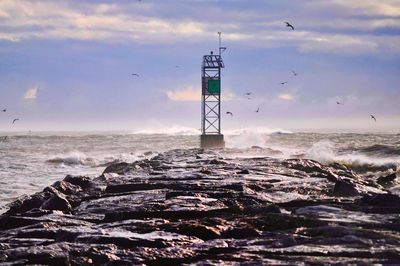 Lighthouse by sea against sky