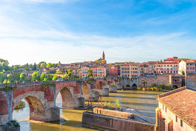 Arch bridge over river against buildings in city