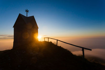 Silhouette cross against sky during sunset