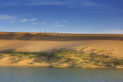 Women carrying water on sand dune
