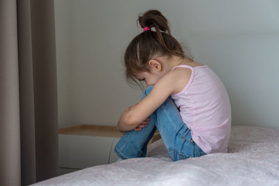 Girl sitting on bed at home