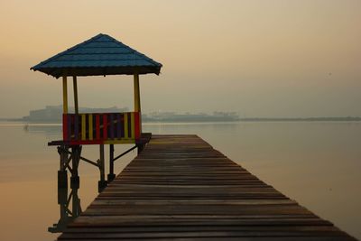 Pier on sea against clear sky during sunset