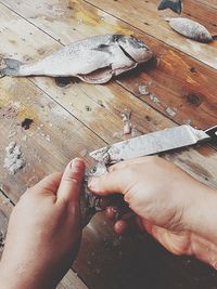 Cropped hand cleaning fish at table