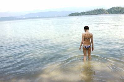 Rear view of a bikini woman in calm sea