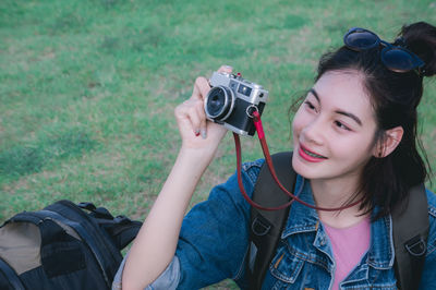 Smiling young woman photographing with camera on field