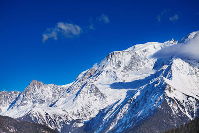 Scenic view of snowcapped mountains against blue sky