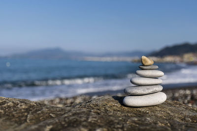 Stack of stones at beach against sky