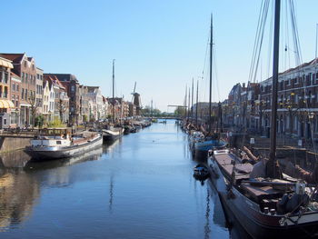 Boats moored at harbor against buildings in city