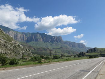 Road by mountains against sky