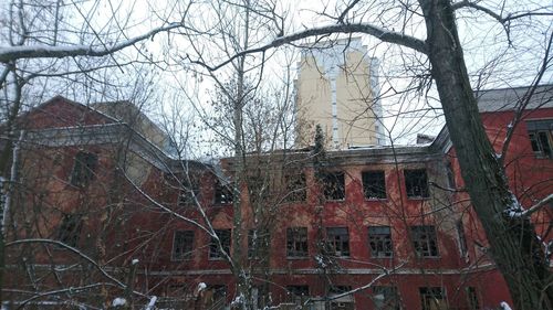 Abandoned building with bare trees in foreground