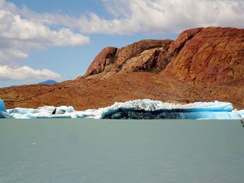 Scenic view of lake and iceberg with mountain range in background