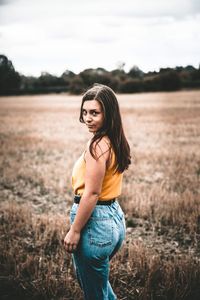 Portrait of smiling young woman standing on field