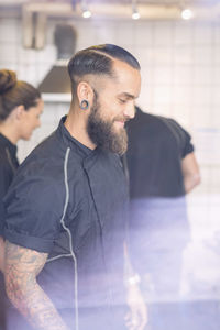 Smiling male worker working with colleagues in candy shop