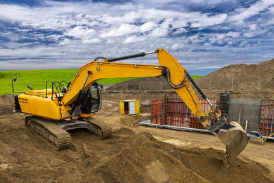 Excavator working on construction site with dramatic clouds on sky