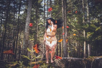 Woman standing by tree in forest