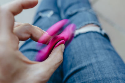 Midsection of person spinning pink fidget spinner