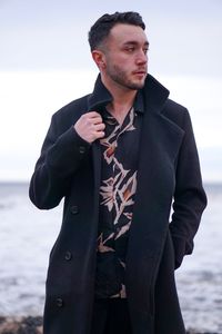 Young man looking at sea against sky