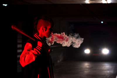 Midsection of man holding red light painting at night