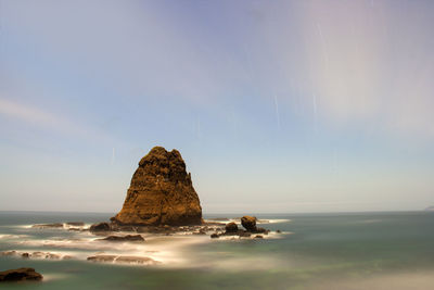 Rock formation in sea against sky