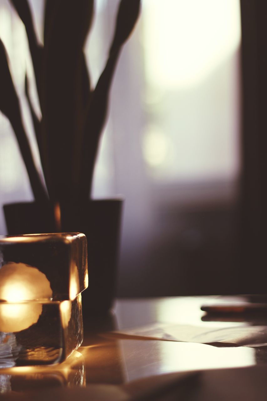 CLOSE-UP OF ILLUMINATED TEA LIGHT CANDLE ON TABLE