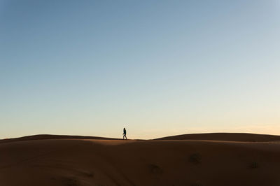 Silhouette of man walking on sand dune