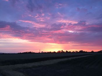 Scenic view of silhouette field against romantic sky at sunset