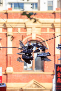 Close up of shoes dangling from a rope between buildings