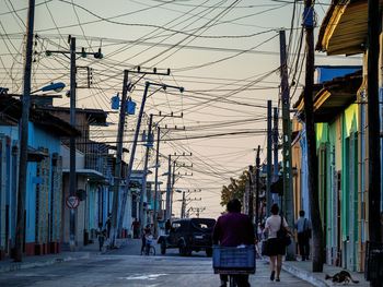 Telephone poles by street in city against sky