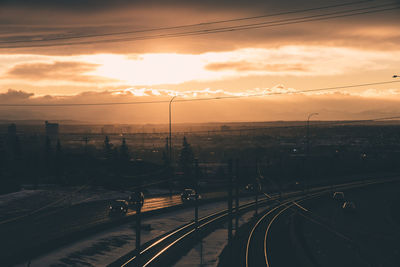 Railroad tracks in city against sky during sunset
