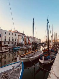 Boats moored at harbor against clear sky