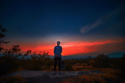 Man standing against orange sky