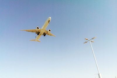 Low angle view of airplane flying against clear blue sky