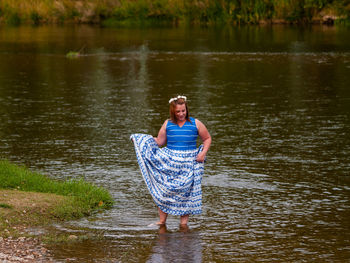Smiling young woman standing in river