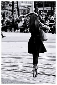 Rear view of woman with umbrella standing on street