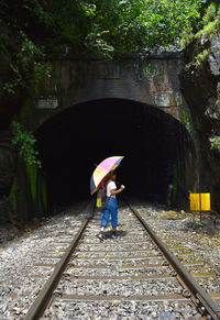 Rear view of woman walking on railroad track