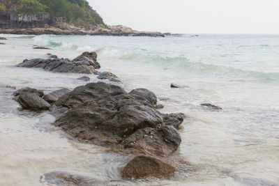 Scenic view of rocks on beach against sky