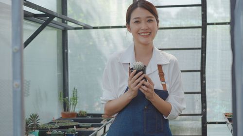 Portrait of a smiling young woman standing against window