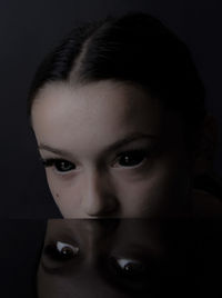 Close-up portrait of young woman against black background