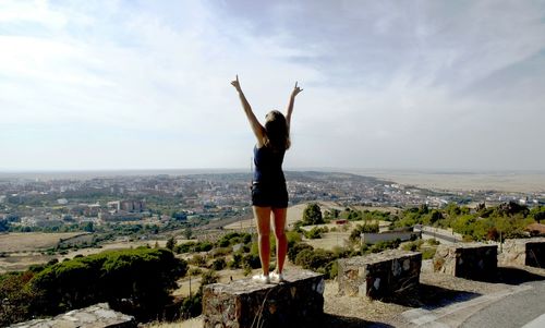 Woman with arms raised standing against cityscape