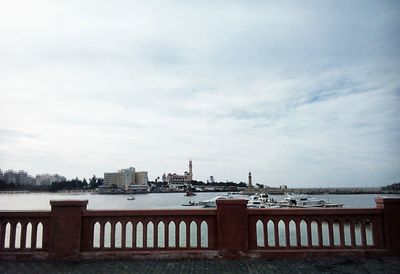 Bridge over river in city against sky