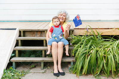 Senior woman holding flag sitting with son on steps