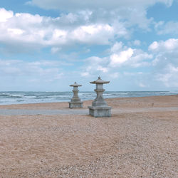 Scenic view of beach against cloudy sky