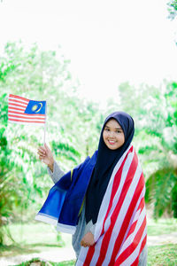 Muslim woman happy holding a malaysian flag. malaysia independence day.