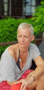 Thoughtful mid adult woman looking away while sitting against plants