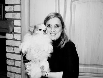 Portrait of smiling woman with dog against door