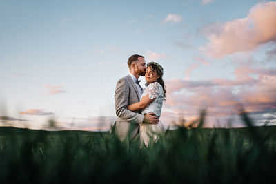 Side view of couple kissing against sky