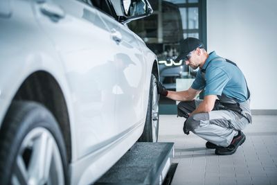 Male mechanic looking at car tire in garage